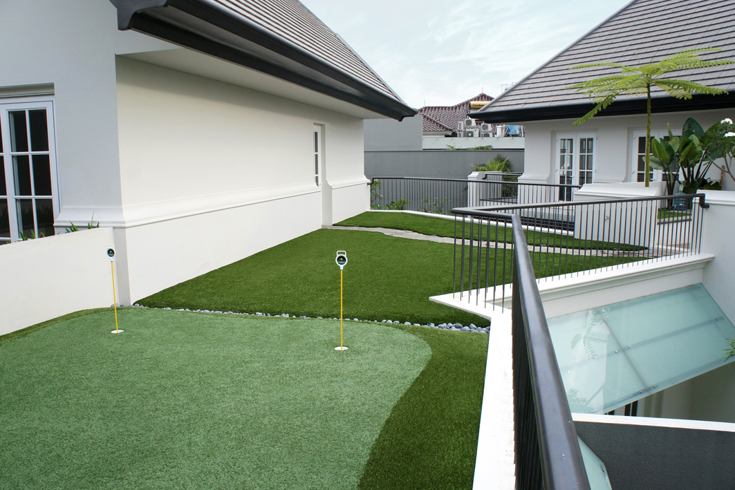 Artificial turf installed in a modern residential courtyard featuring a custom backyard putting green, clean landscape borders, and low-maintenance synthetic grass for year-round curb appeal.